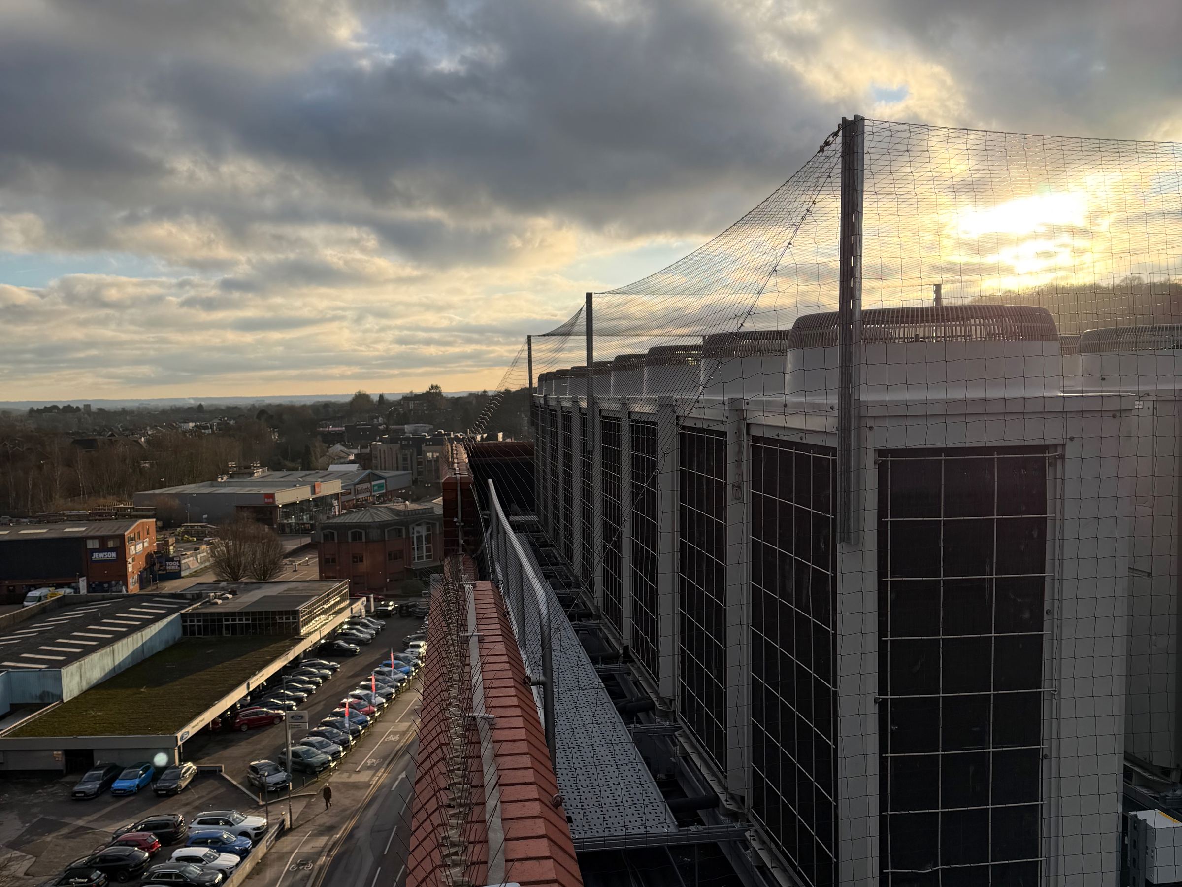 Rooftop air conditioning units enclosed in bird netting at sunset