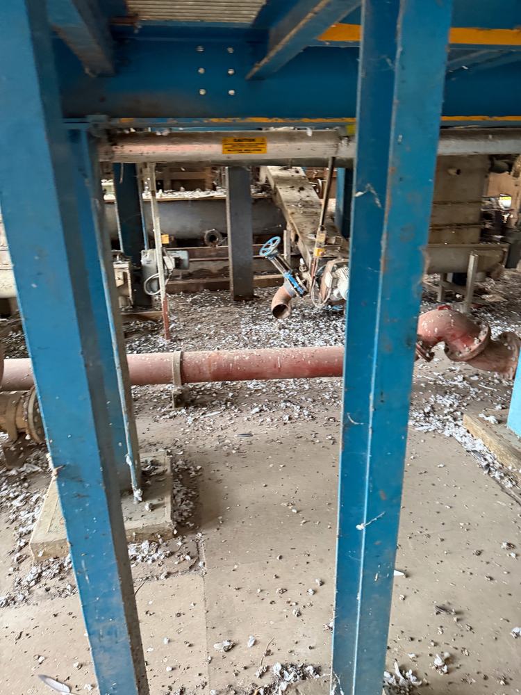 Before: floor covered in pigeon droppings around blue steel columns in an industrial unit